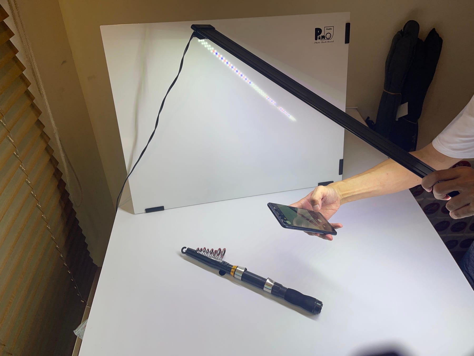 撮影ボックスと照明を使用して釣り竿を撮影している作業